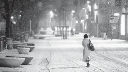  ?? JEAN-FRANCOIS BADIAS/AP ?? A woman walks after curfew Thursday in Strasbourg, France. Trying to avoid a third national lockdown, France is opting for creeping curfews. The country will restrict movement from 6 p.m. to 6 a.m. daily starting Saturday.