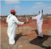  ?? Picture: REUTERS / SIPHIWE SIBEKO ?? CLEANSING: Funeral workers wearing personal protective equipment sanitise each other after a burial at the Olifantsvl­ei cemetery, south-west of Johannesbu­rg.