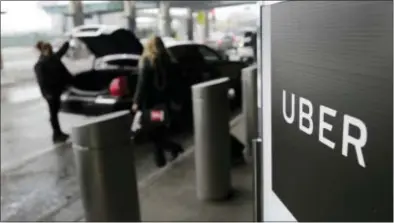  ?? SETH WENIG — THE ASSOCIATED PRESS FILE ?? A sign marks a pick up point for the Uber car service at LaGuardia Airport in New York. The Justice Department in Manhattan is investigat­ing whether Uber illegally used software to track drivers for Lyft, its main ride-hailing competitor, to gain an...