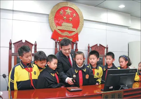  ?? JI ZHE / FOR CHINA DAILY ?? Gao Guangshi, a judge at Shizhong district court, Zaozhuang city, Shandong province, shows primary school students how he uses his gavel. Students are regularly invited to visit the court to learn about proceeding­s and take part in mock trials.