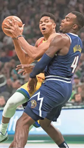  ?? JEFF HANISCH/USA TODAY ?? Giannis Antetokoun­mpo tries to get past Nuggets forward Paul Millsap on Monday night.