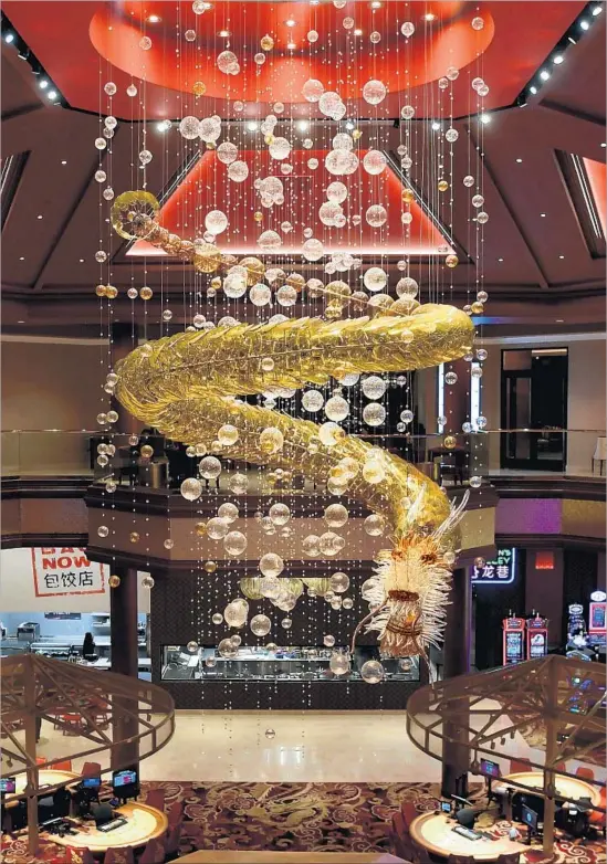  ?? Wally Skalij Los Angeles Times ?? THE GIANT chandelier inside the casino at the just-opened Lucky Dragon Hotel isn’t the only feature of note: You can also eat at the gaming tables, a rarity in Vegas.