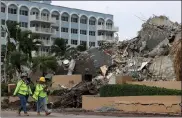  ?? Joe raedle / getty images ?? Workers helping with the search and rescue walk along collins avenue past the completely collapsed 12-story champlain towers south on tuesday in surfside, Fla.