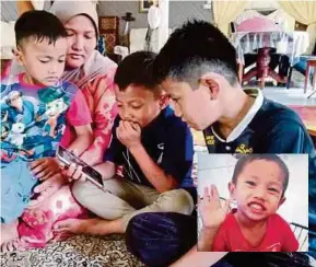  ?? (FOTO NOOR HIDAYAH TANZIZI /BH) ?? Sofiah Mohd Teridi bersama tiga anaknya melihat foto Muhamad Anas (gambar kecil) yang maut selepas terjatuh ke dalam lubang kumbahan di Kuarters Balai Polis Pasir Puteh, Ipoh.