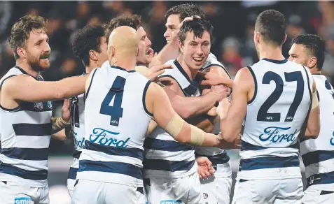  ??  ?? Jack Henry of the Cats (third from right) is mobbed by teammates after kicking his first AFL goal. Picture: AAP