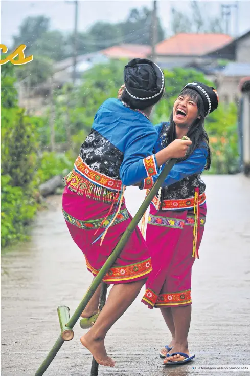  ??  ?? Lua teenagers walk on bamboo stilts.