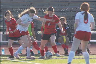  ?? Daniel Bereznicki/McDonald County Press ?? The Lady Mustang soccer team came head-to-head against New Covenant Academy on March 19. Anna Clarkson (No. 14) and Valery Flores (No. 4) tag team to get the ball to the center of the field.