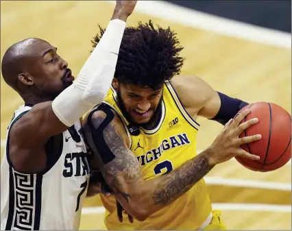  ?? PHOTOS BY CARLOS OSORIO — THE ASSOCIATED PRESS ?? Michigan forward Isaiah Livers (2) is defended by Michigan State guard Joshua Langford (1) during the first half of Sunday’s game in East Lansing.