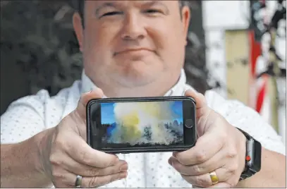  ?? Elaine Thompson The Associated Press ?? Jason Ritchie holds his phone Friday with a photo he took of a wildfire behind his home four years earlier in Sammamish, Wash.