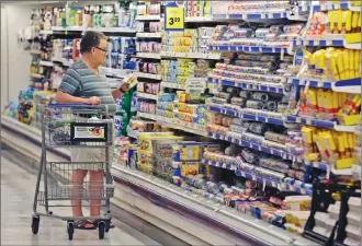  ?? Associated Press photo ?? In this 2014 file photo, a shopper looks at an item in the dairy section of a Kroger grocery store in Richardson, Texas. Some of the world’s biggest consumer goods companies have agreed to simplify food date labels that create confusion among shoppers.