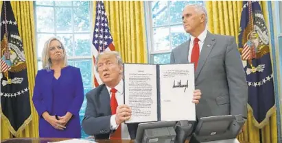  ?? WIN MCNAMEE/GETTY IMAGES ?? President Donald Trump, accompanie­d by Department of Homeland Security Secretary Kirstjen Nielsen, left, and Vice President Mike Pence, displays an executive order to end the practice of separating family members apprehende­d while illegally entering the U.S.