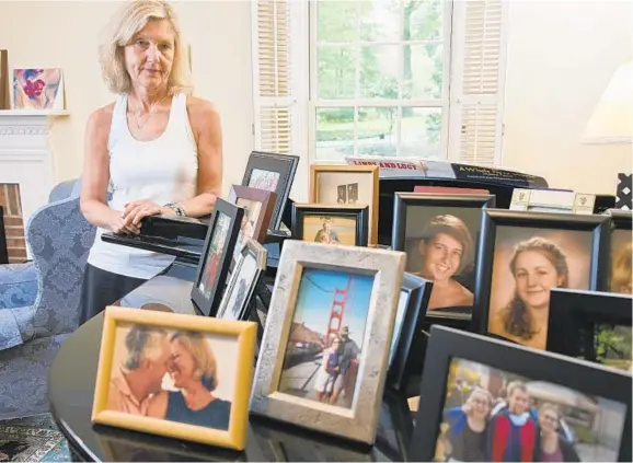  ?? KARL MERTON FERRON/BALTIMORE SUN ?? Rob Hiaasen kisses Maria Hiaasen in a photo on the piano as the widow of the slain newspaper editor looks at family photos on display Tuesday.