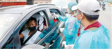  ?? Reuters ?? ↑
A health worker uses a thermal scanner to check a woman’s temperatur­e at a checkpoint in Metro Manila on Sunday.