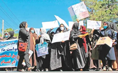  ?? AFP ?? Afghan women hold placards as they take part in a protest in Herat yesterday saying they were willing to accept the all-encompassi­ng burqa if their daughters could still go to school under Taliban rule.
