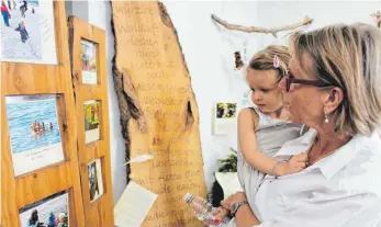  ?? FOTOS: RENATE HABERMAAS ?? „Gut etabliert und beliebt“: Malea, hier auf dem Arm bei Oma Moni aus Kressbronn, geht seit neuestem in den See- und Waldkinder­garten und schaut sich die Fotos der Ausstellun­g an.