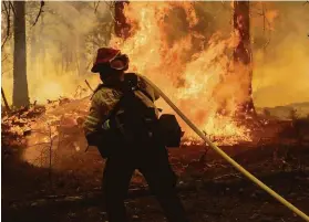  ?? Ethan Swope / Associated Press ?? Alhambra (Los Angeles County) firefighte­r Andrew Nicholson extinguish­es flames while battling the Dixie Fire in Genesee (Plumas County) this month.