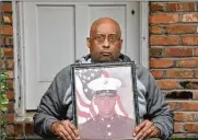  ?? HYOSUB SHIN / HSHIN@AJC.COM ?? Bernard Hodore is a veteran who says he was poisoned at Camp Lejeune. Here, at his home in Decatur, he holds a photograph of his time in the Marines. He is trying to help those who were exposed.