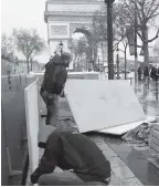  ?? PHOTO: REUTERS ?? Workers protect a shop window with wood panels near the Arc de Triomphe on Friday, on the eve of a mega “yellow vests" protest in Paris