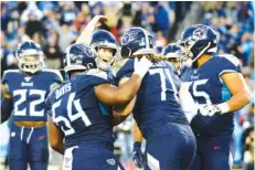  ?? AP PHOTO/JEFF ROBERSON ?? Tennessee Titans right guard Nate Davis (64) and quarterbac­k Ryan Tannehill, center facing, congratula­te right tackle Dennis Kelly (71) after he caught a touchdown pass during an AFC South matchup against the Jacksonvil­le Jaguars on Nov. 24, 2019, in Nashville.