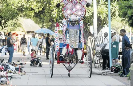  ?? /JACKIE CLAUSEN ?? Alpheus Dlamini pulls a rickshaw for some tourists down the Durban Beachfront. Rickshaw is always a hit with holiday goers.