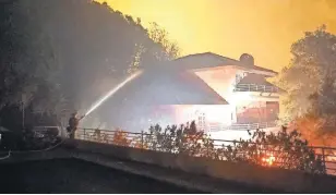  ?? TREVOR HUGHES, USA TODAY ?? Firefighte­r Eric James hoses off the roof of a home Tuesday near Kenwood, Calif., as a wildfire approaches. A stray ember could be the seed of widespread destructio­n.