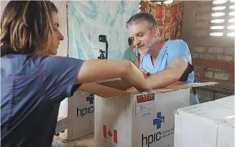  ?? ?? HPIC board member and medical mission volunteer Dr. Pierre Plourde unpacking a Humanitari­an Medical Kit to stock a small clinic in Haiti.