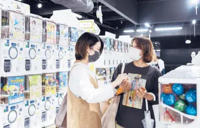  ?? NORIKO HAYASHI/THE NEW YORK TIMES ?? Two women at a Tokyo store with over 3,000 gachapon vending machines. The machines dispense toys in small plastic capsules. Hundreds of products are introduced monthly and videos of gachapon spending sprees have gone viral.