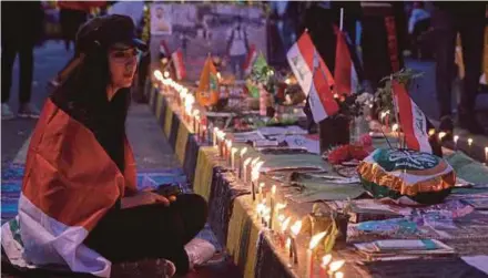  ?? AFP PIC ?? A woman holding a candleligh­t vigil at Tahrir Square in Baghdad on Thursday for her comrades who were killed in anti-government demonstrat­ions recently.