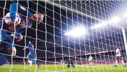  ?? AP ?? Lionel Messi marcó un doblete frente al Valencia y se despegó en el goleo con 25 anotacione­s. Uno de los tantos de ayer lo hizo de penal; aquí cuando recogió la pelota de la red.