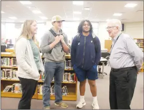  ?? (NWA Democrat-Gazette/Lynn Kutter) ?? John Wyatt, a full-time substitute teacher at Prairie Grove High School, visits with Reese Light, who is his granddaugh­ter; Corbin Bowlin; and James Moss in the Prairie Grove High School library.