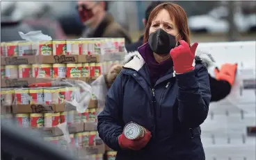  ??  ?? Mary Oster and other volunteers hand out groceries at a food drive sponsored by the Connecticu­t Food Bank at Calf Pasture Beach in Norwalk on Wednesday. The event replicates Foodshare’s emergency drive-thru food distributi­on at Rentschler Field in East Hartford.