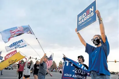  ?? Andy Cross, The Denver Post ?? Anna Von Hoene, right, 18, from Highlands Ranch, shows her support for former Vice President Joe Biden on Tuesday in the middle of a gathering of President Donald Trump supporters at the intersecti­on of Highlands Ranch Parkway and University Boulevard.