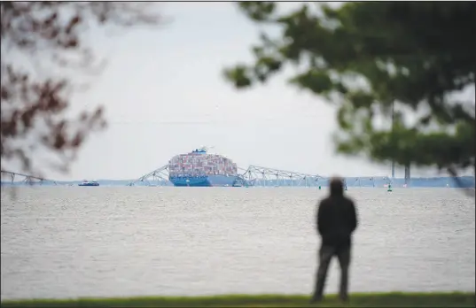  ?? MATT ROURKE / ASSOCIATED PRESS ?? From Fort Mchenry, a person views the Dali container ship as it rests against the wreckage of the Francis Scott Key Bridge on Thursday in Baltimore. “This is no ordinary bridge. This is one of the cathedrals of American infrastruc­ture,” U.S. Transporta­tion Secretary Pete Buttigieg said during a news conference last week in Baltimore.