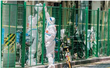  ?? Photo: EPA ?? Protective gear is exchanged amid the lockdown in Shanghai, where more than 70 new cases have been found in presumed low-risk zones.