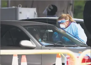  ?? Wilfredo Lee / Associated Press ?? A health care worker prepares to test a driver in line at a drive-thru COVID-19 testing site outside Hard Rock Stadium in Miami Gardens, Fla., on Wednesday.
