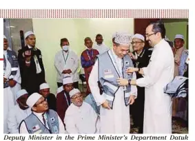  ?? PIC COURTESY OF TABUNG HAJI ?? Deputy Minister in the Prime Minister’s Department Datuk Asyraf Wajdi Dusuki presenting the Sahabat Maktab vest to a a volunteer in Mecca.