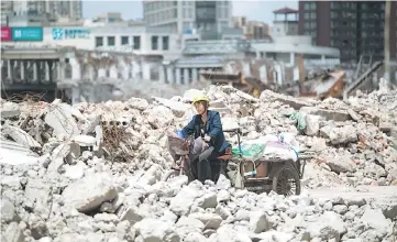  ??  ?? A migrant worker on her tricycle at the demolition site of the Jiuxing furniture market in the suburbs of Shanghai. Moody’s ratings agency downgraded China’s credit score for the first time since 1989 on fears that the country will struggle to tame its...