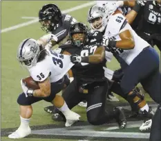  ?? AP photo ?? Nevada offensive lineman Aaron Frost (65) tries to keep Hawaii defensive lineman Zach Ritner (97) from pulling down Wolf Pack running back Toa Taua (35) on Saturday.