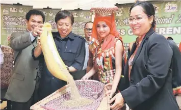  ??  ?? Abang Johari (second left) pours rice to a traditiona­l threshing basket while Ik Pahon (left) and Jane (right) look on. — Photo by Kong Jun Liung