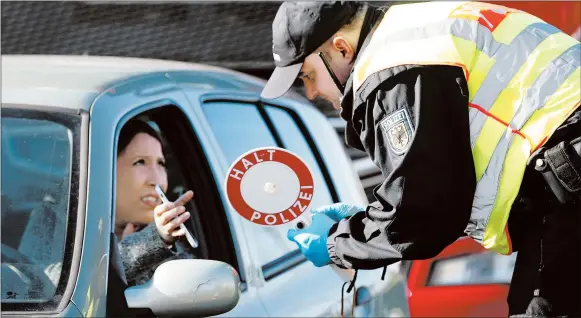  ?? JEAN-FRANCOIS BADIAS/AP ?? A German police officer checks authorizat­ion for a woman to enter from France.