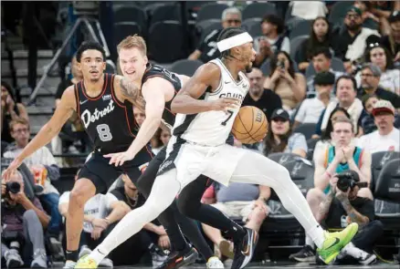 ?? ?? San Antonio Spurs guard David Duke, Jr., (right), drives the ball against Detroit Pistons guards Buddy Boeheim (center), and Jared Rhoden (left), during the second half of an NBA basketball game, Sunday, April 14, 2024, in San Antonio. (AP)