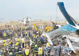  ??  ?? Equipes de resgate observam os destroços do avião em Katmandu