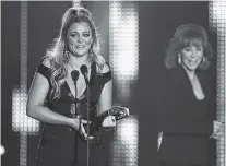  ??  ?? Lauren Alaina accepts the award for breakthrou­gh video of the year for “Road Less Traveled” at the CMT Music Awards at Music City Center on Wednesday in Nashville. Looking on in background right is presenter Reba McEntire.