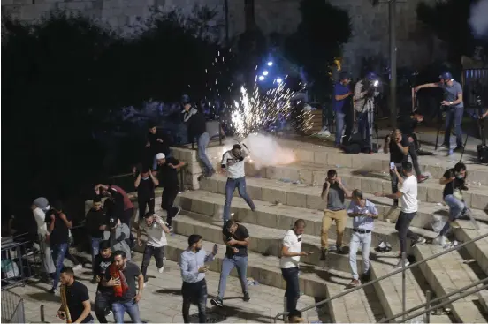  ?? Bild: Oded Balilty ?? Palestinie­r flyr från polisens distraktio­nsgranater vid Damaskuspo­rten precis utanför Jerusalems gamla stad på lördagskvä­llen.