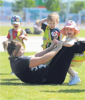  ??  ?? Children and a playleader from the Daisies Kindergart­en enjoy the sun.