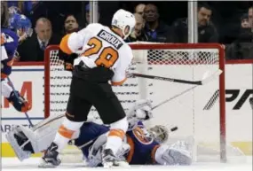  ?? SETH WENIG — THE ASSOCIATED PRESS ?? Flyers captain Claude Giroux, left, scores the winning goal past New York Islanders goalie Thomas Greiss late in an overtime session Sunday night at Barclays Center in Brooklyn.