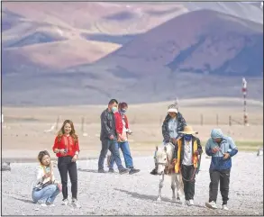  ??  ?? Tourists walk along the lakeshore and ride a pony in Namtso.