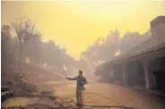  ?? MARCIO JOSE SANCHEZ/ASSOCIATED PRESS ?? Marco Alcaraz uses a garden hose to protect his girlfriend’s home as the Easy Fire approaches Wednesday in Simi Valley, Calif.