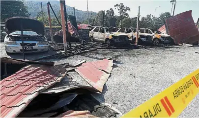 ??  ?? Gutted: The damaged vehicles at the Kuala Kangsar Road Transport Department after they were set on fire.