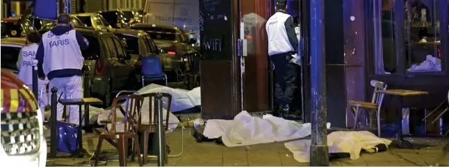  ??  ?? State of emergency: The bodies of victims of last night’s atrocity lie under bloodstain­ed blankets at a Paris restaurant. It was one of at least five terror targets